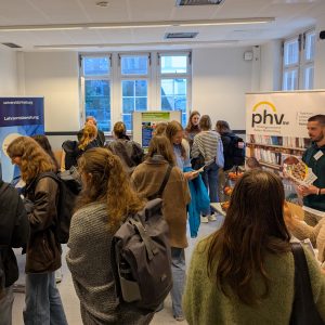 Viele Studierende informieren sich in einem Raum mit verschiedenen Info-Ständen.