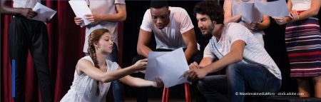 Sieben junge Menschen stehen auf einer Theaterbühne und erarbeiten gemeinsam den Text bzw. die Szene.