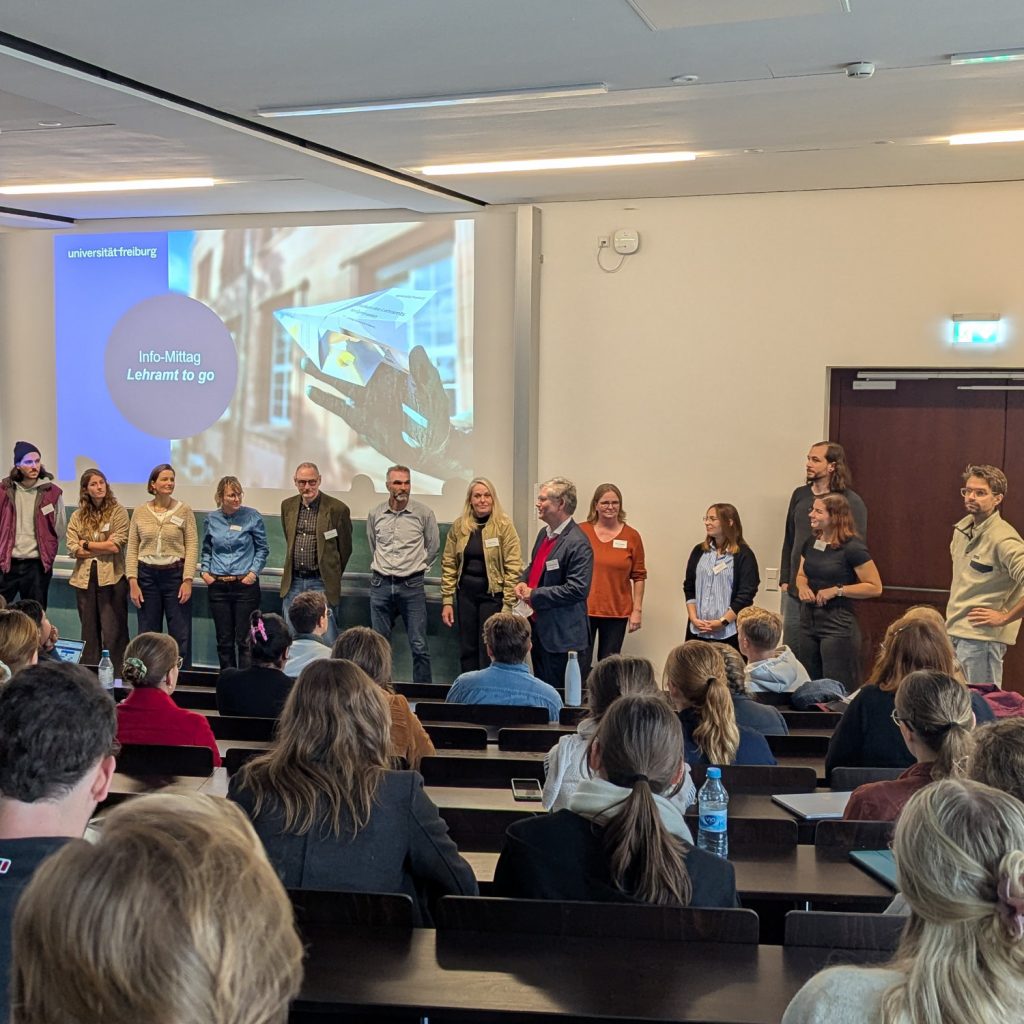 Im Hörsaal stellen sich alle Aussteller der veranstaltung kurz den Studierenden vor. Im Hintergrund ist der Veranstaltungshinweis zu sehen.
