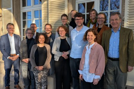 Die Teilnehmer*innen der Sitzung stehen lächelnd vor der Villa im Sonnenlicht