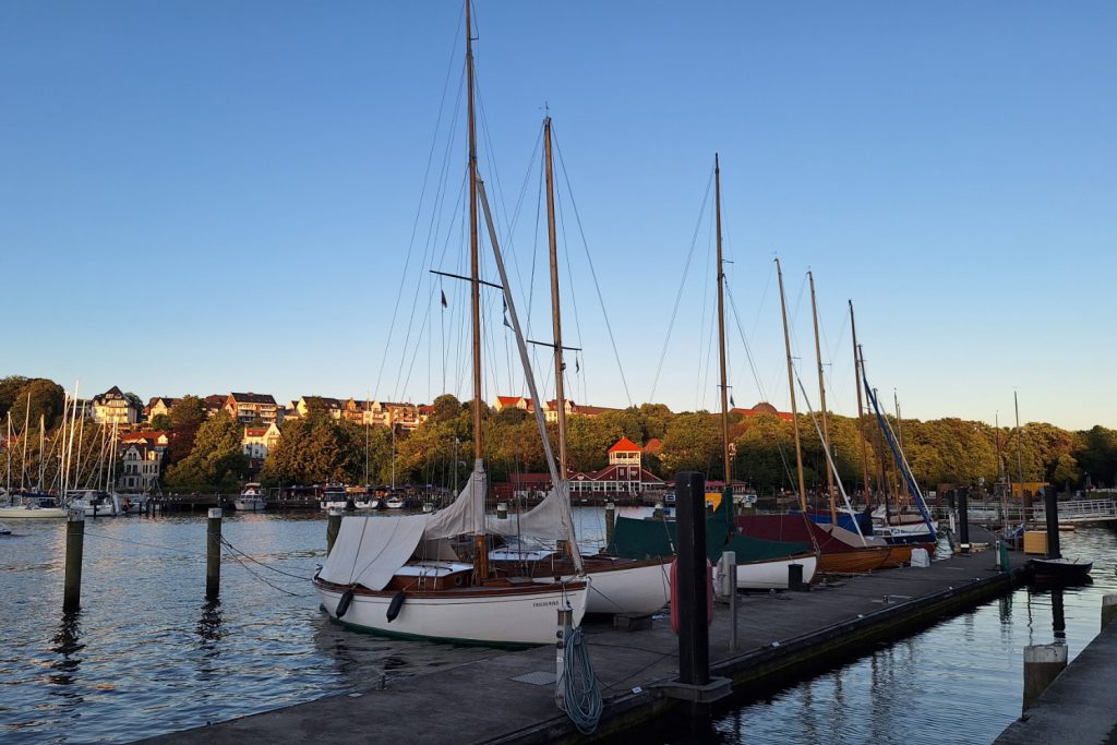 Die Flensburger Förde mit einigen Segelbooten am Pier bei Sonnenuntergang