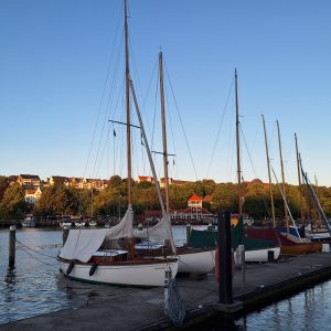 Die Flensburger Förde mit einigen Segelbooten am Pier bei Sonnenuntergang