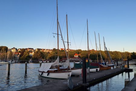 Die Flensburger Förde mit einigen Segelbooten am Pier bei Sonnenuntergang